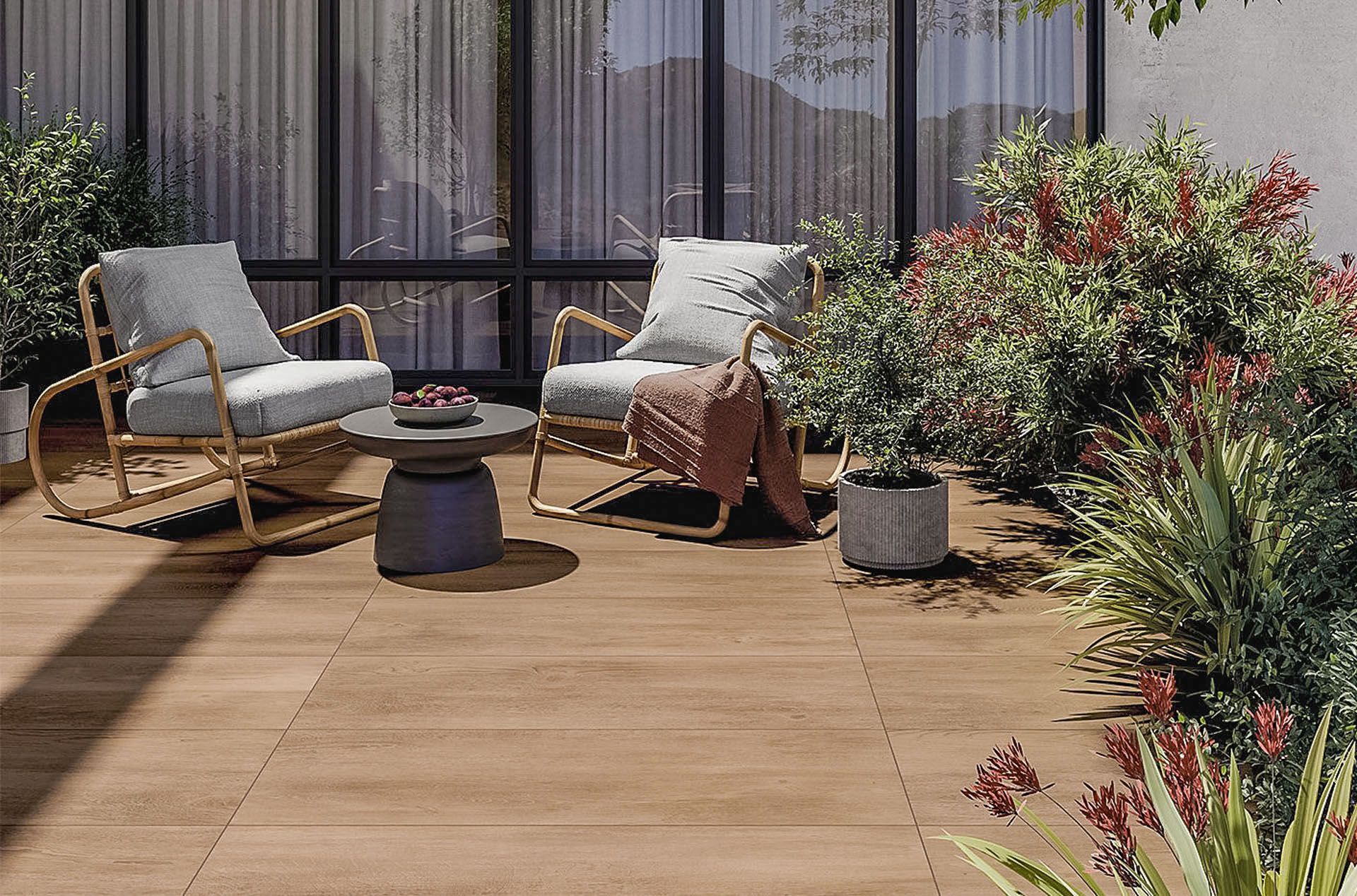 Eine Terrasse mit Fliesen in Holzdekor mit Stühlen und einem Tisch vor einem Fenster.