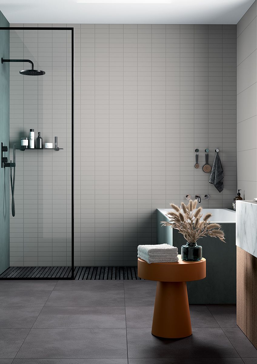 Ein Badezimmer mit gefliesten Wänden, Badewanne, Waschbecken, Dusche und Tisch.