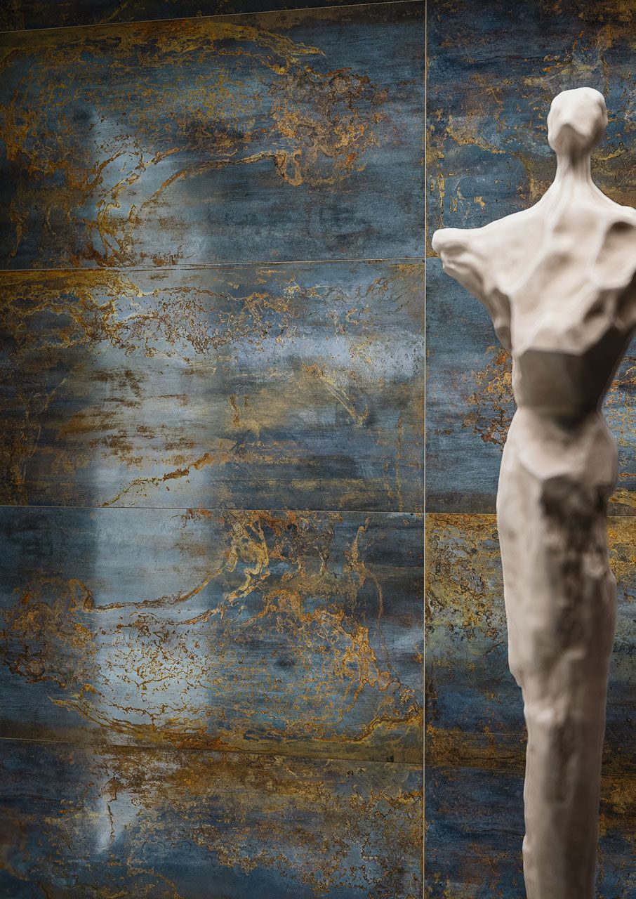 Eine Statue, die vor einer modernen Wandfiese steht.