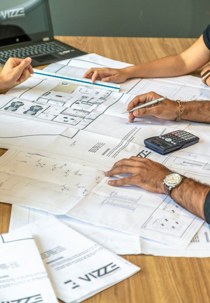 Eine Gruppe von Leuten sitzt an einem Tisch und sieht sich Baupläne an.
