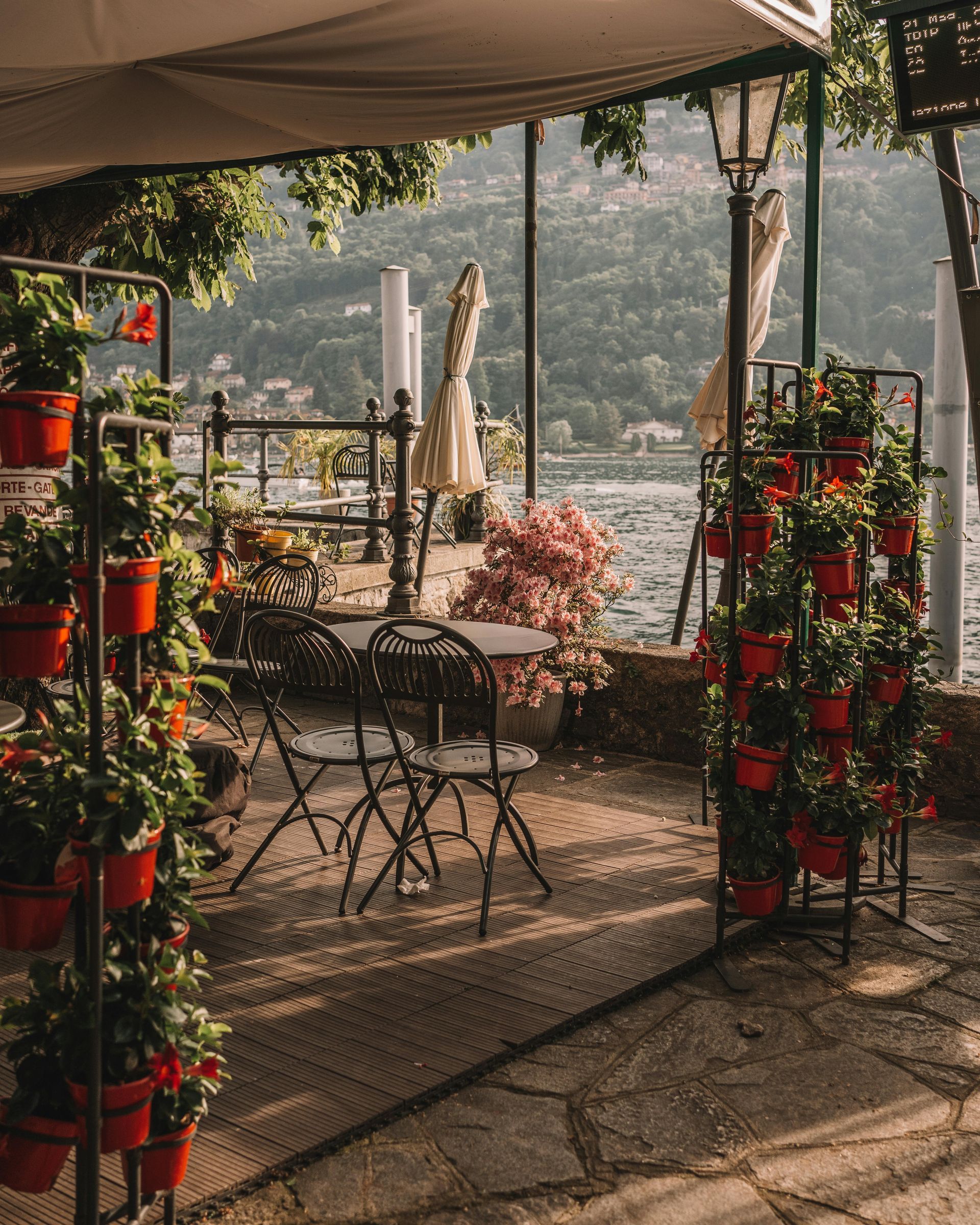 Eine geflieste Terrasse mit Tischen und Stühlen und Topfpflanzen.