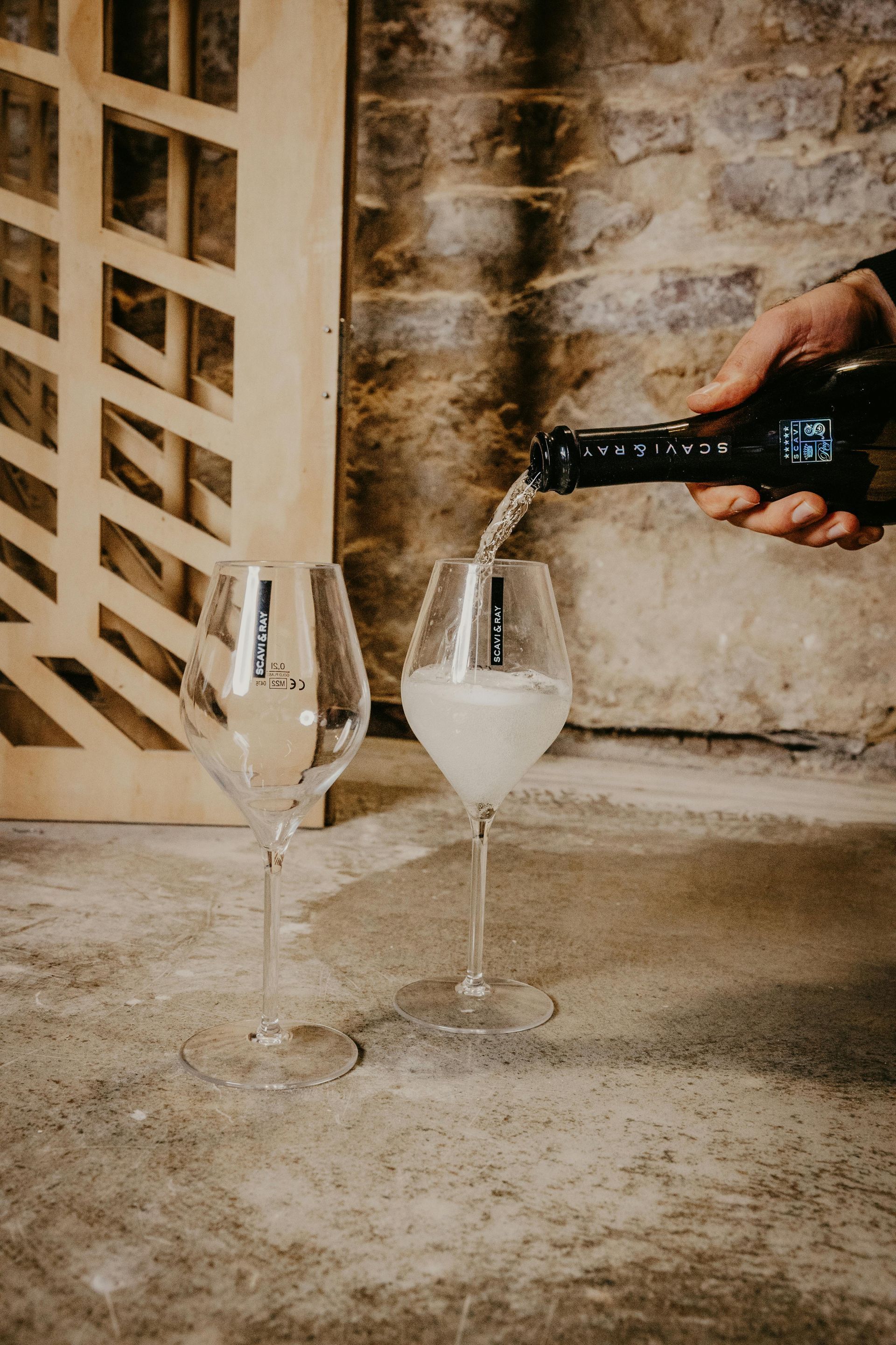 Eine Person gießt Wein in zwei Weingläser.