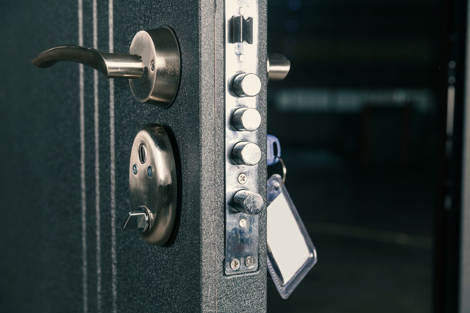 Close-up of a dark metal door with a multi-bolt locking system; keys hang from the lock.