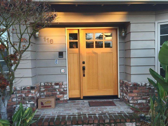 Wooden front door of a house with sidelight windows, brickwork, and address 