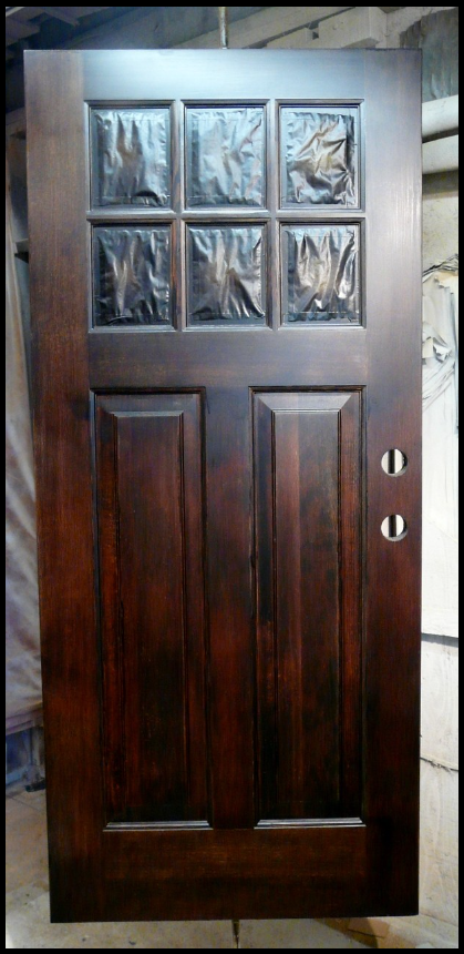 Dark wooden door with six window panes covered, two handles.