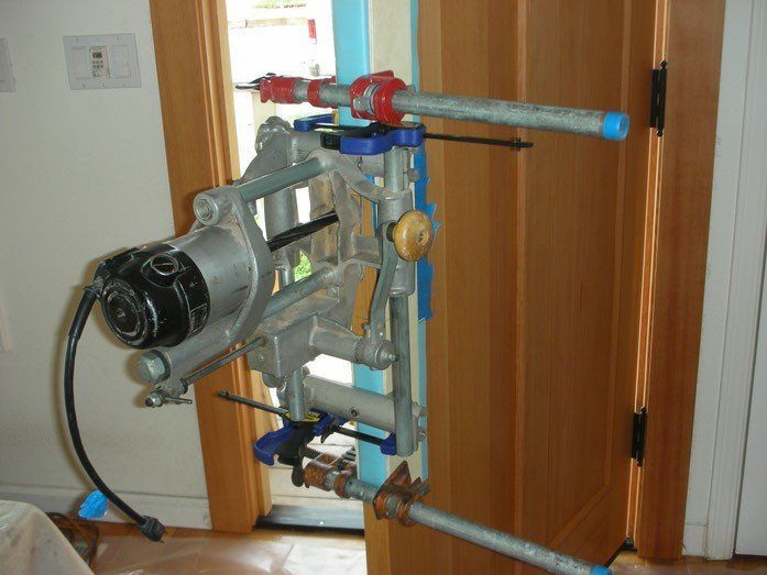 Silver power tool mounted on a pipe frame, positioned near a wooden door frame.