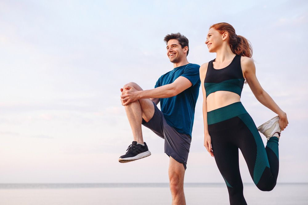 Man and Woman Stretching Their Legs on the Beach — Uniforms2U in Penrith, NSW