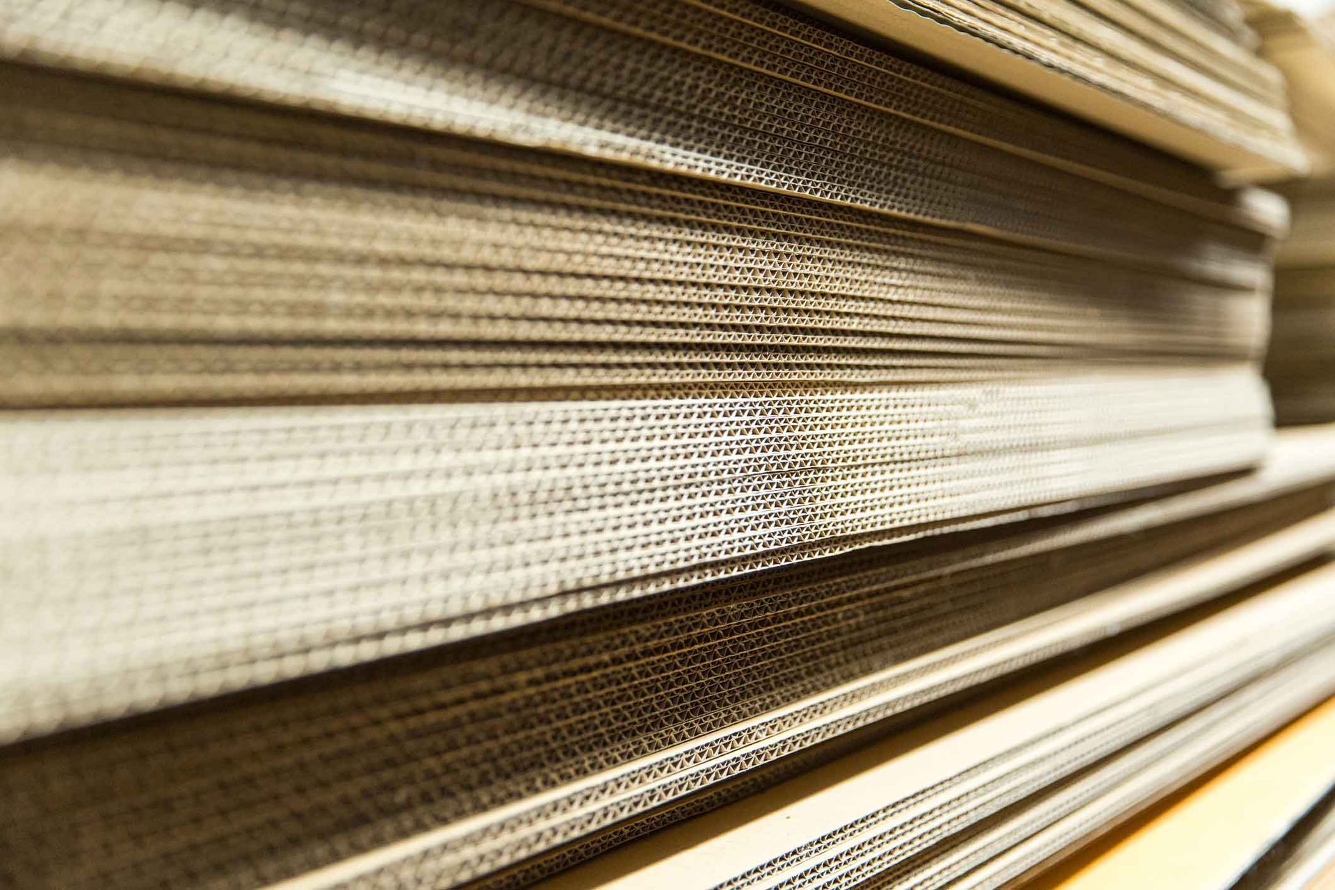 Close-up of stacked corrugated cardboard sheets arranged neatly in a warehouse.