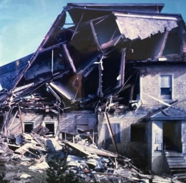 Damaged brick building with collapsed roof and debris.