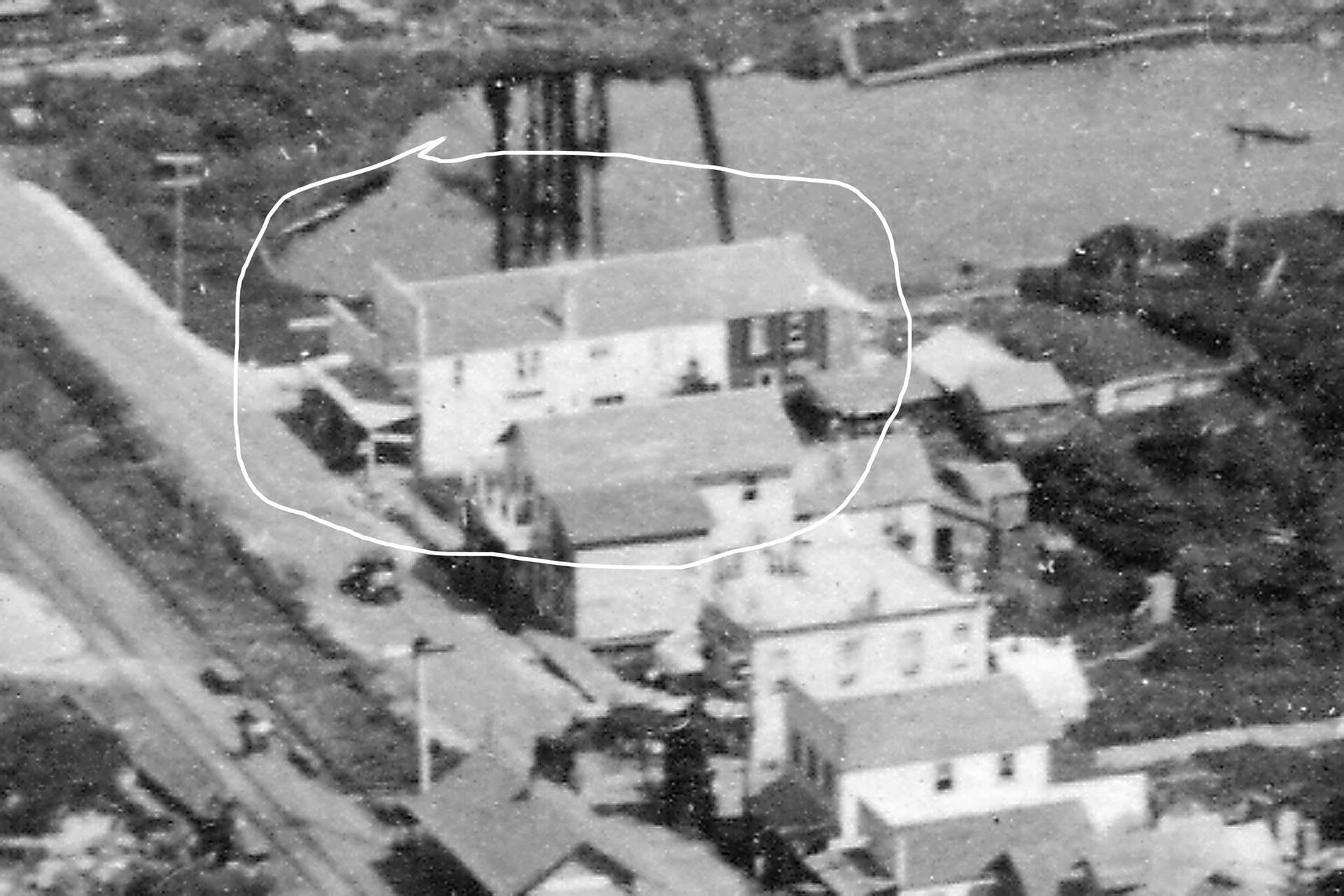 An aerial view of a multi-story building and surrounding structures next to a lake.