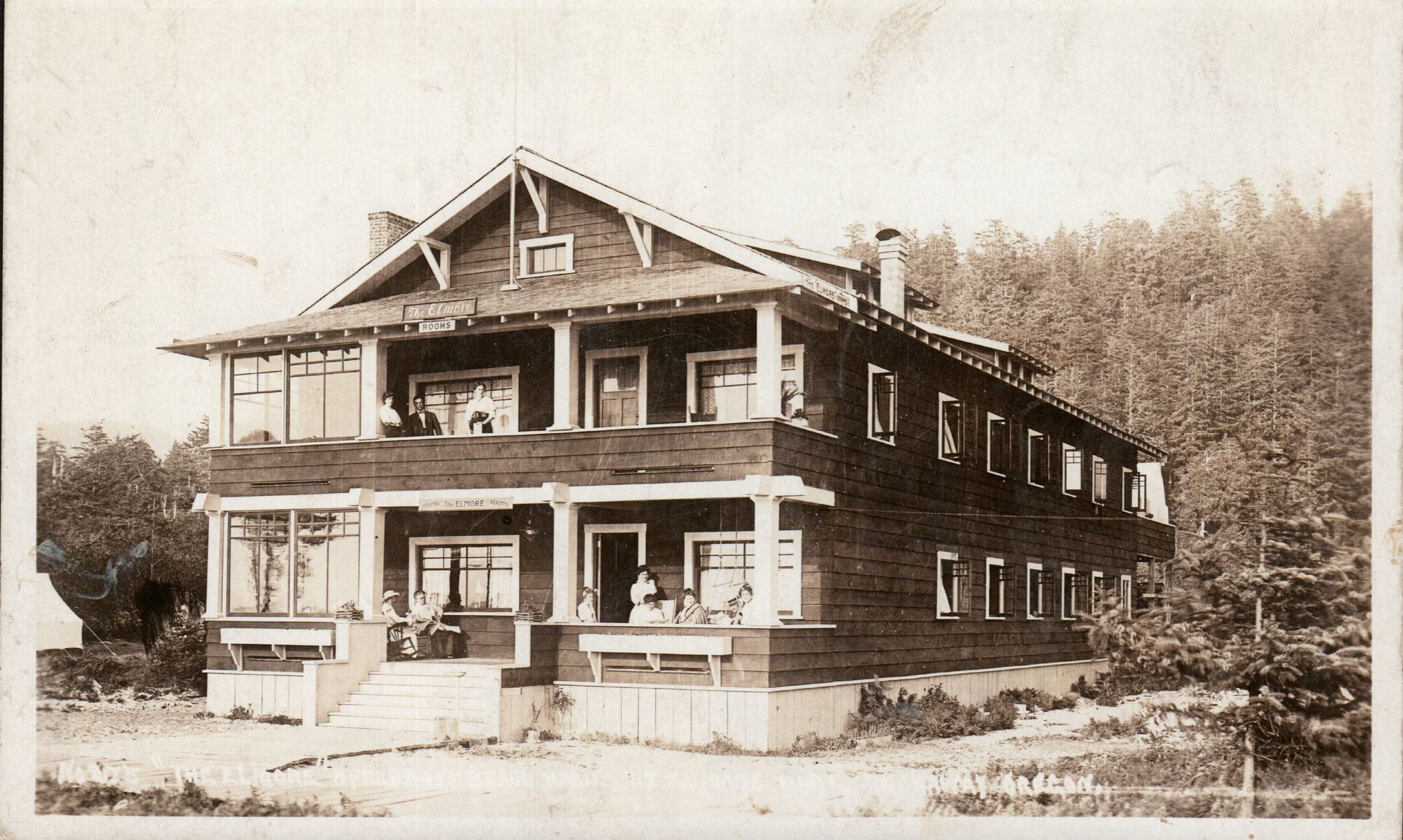 Vintage photo of the Hotel, a large building with a covered porch and unique angled windows on a sandy hillside.