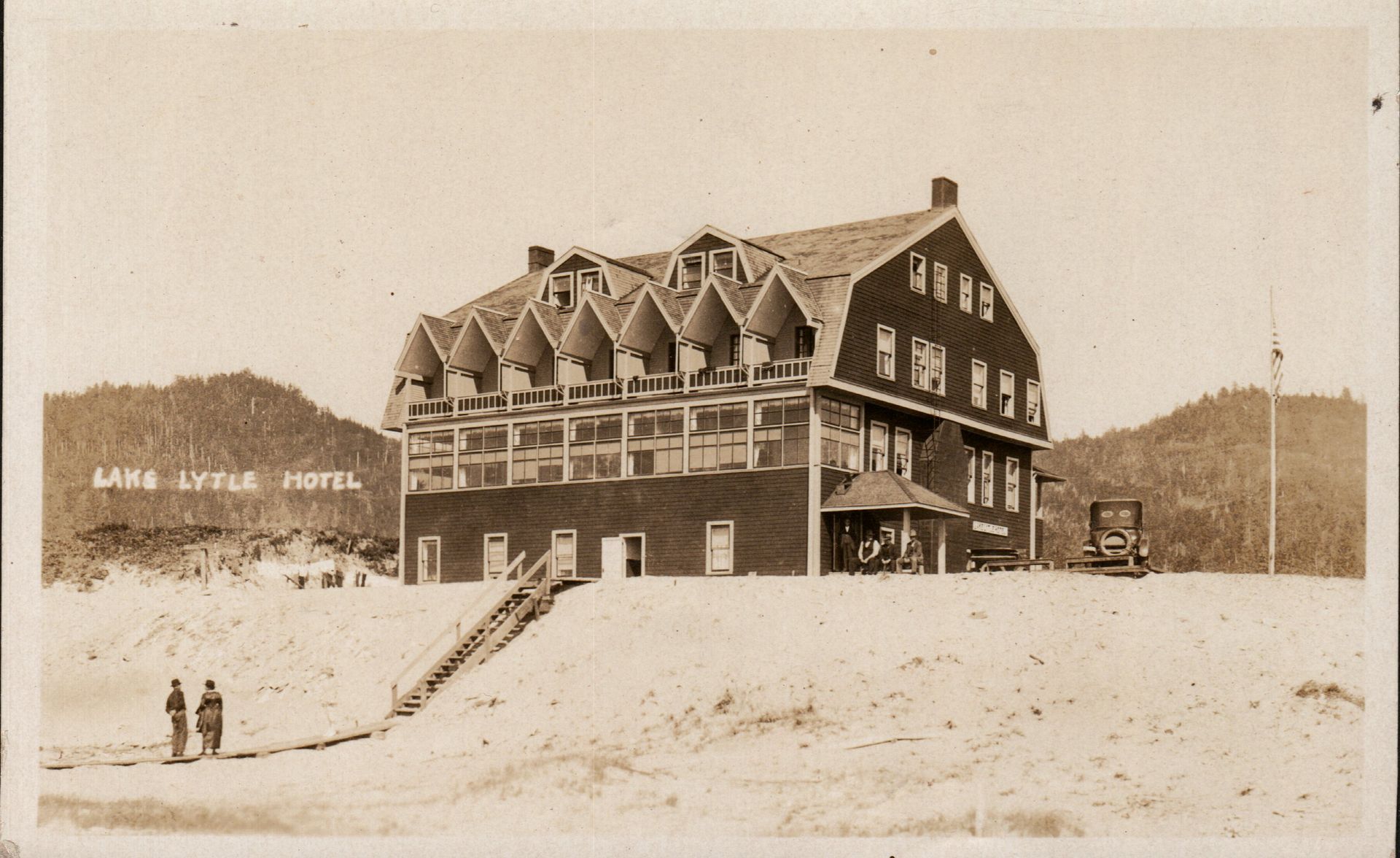 Lake Lytle Hotel, three-story building with dormer windows, wooden siding, men standing outside, sand dune setting.