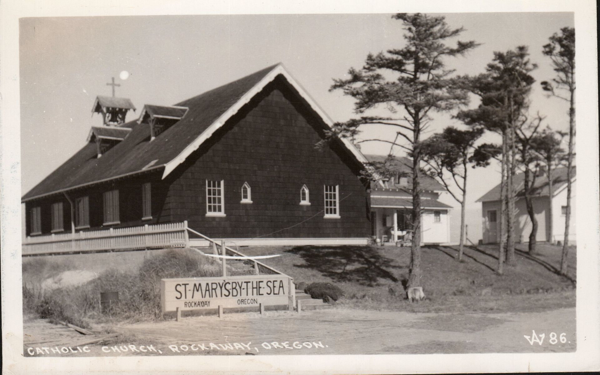Black and white photo of St. Mary's church. Wooden building with sign reading 