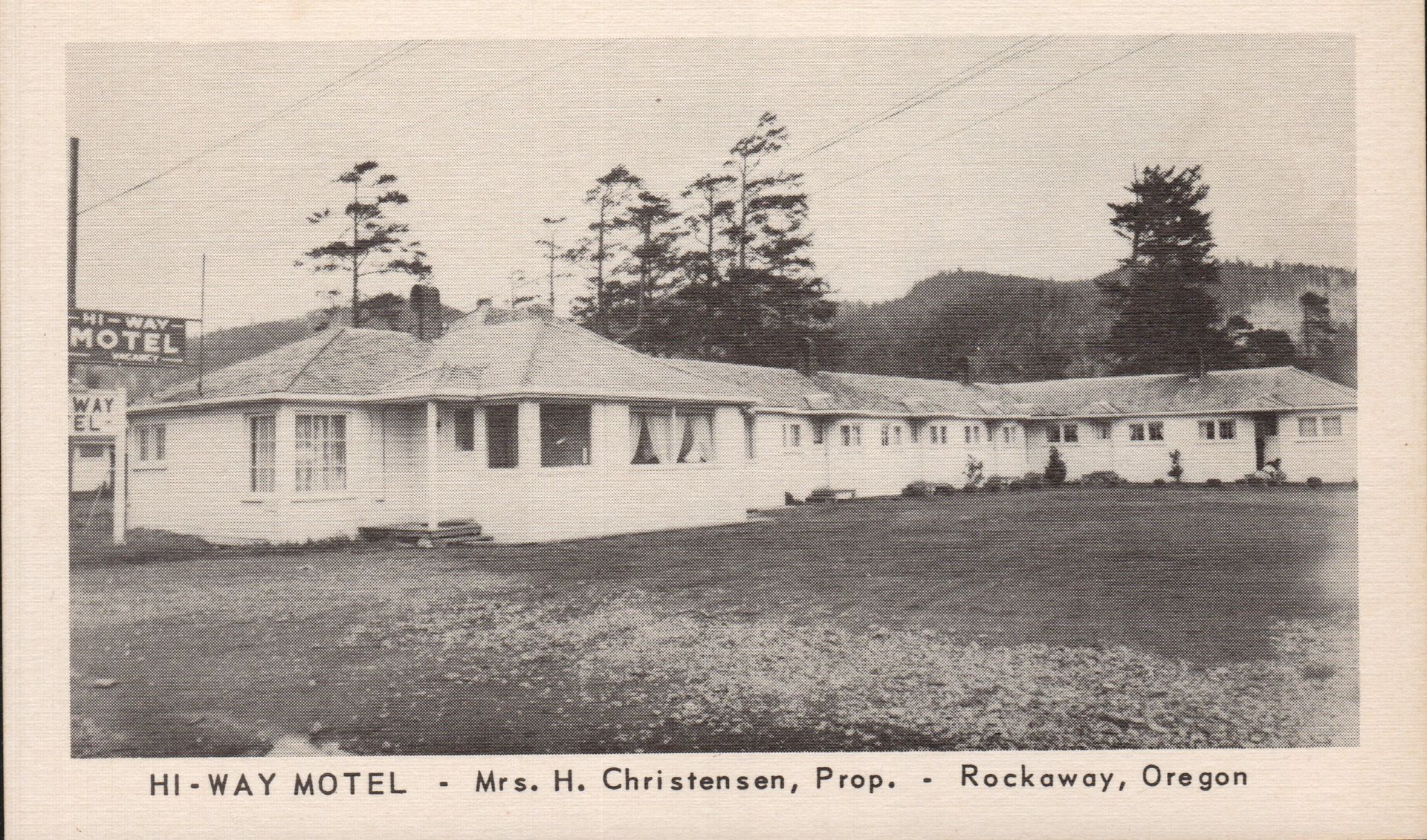 Black and white photo of the Hi-Way Motel in Rockaway, Oregon. A one-story motel with a sign.