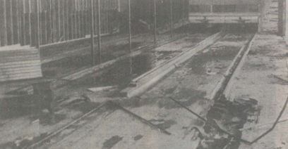 dismantled bowling alley; dark water, long metal supports, and gutters are visible.