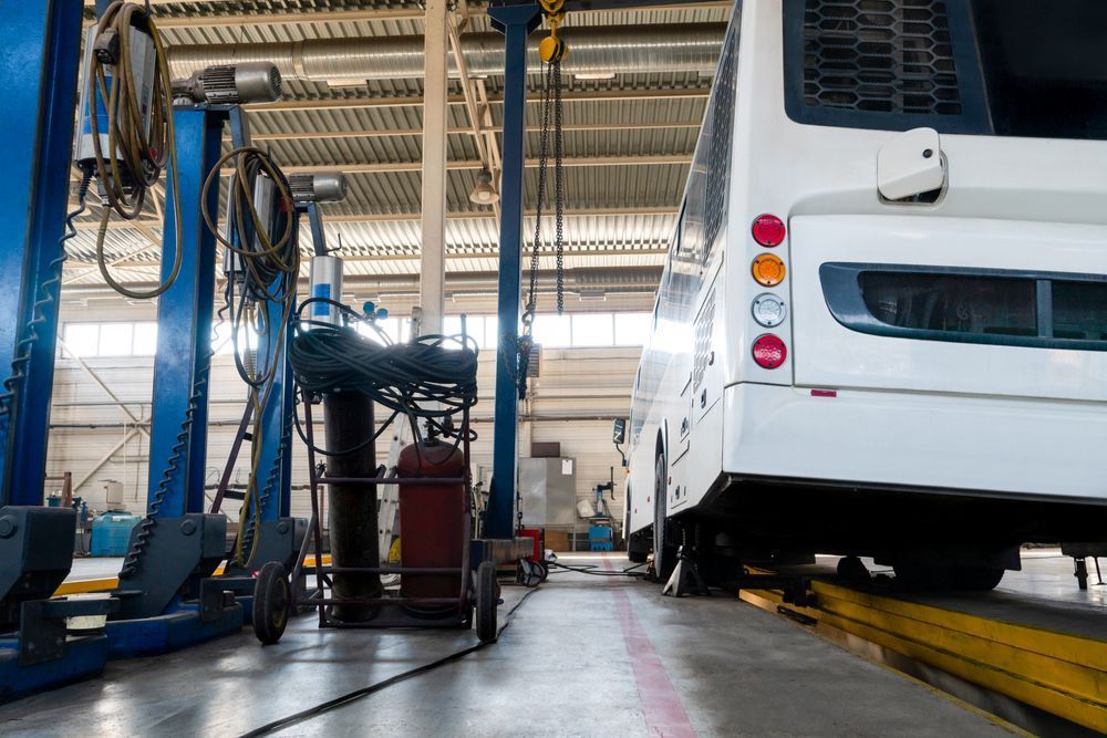 A White Bus is Sitting on a Lift in a Garage — A & J Diesel Services in Braitling, NT