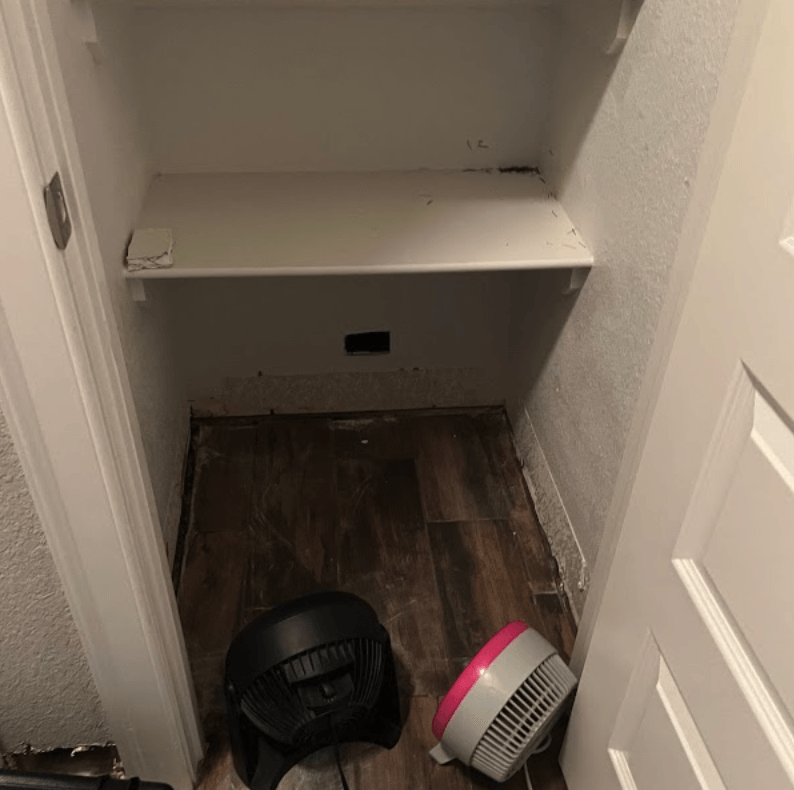 Empty closet with two fans drying broken pipe water damage