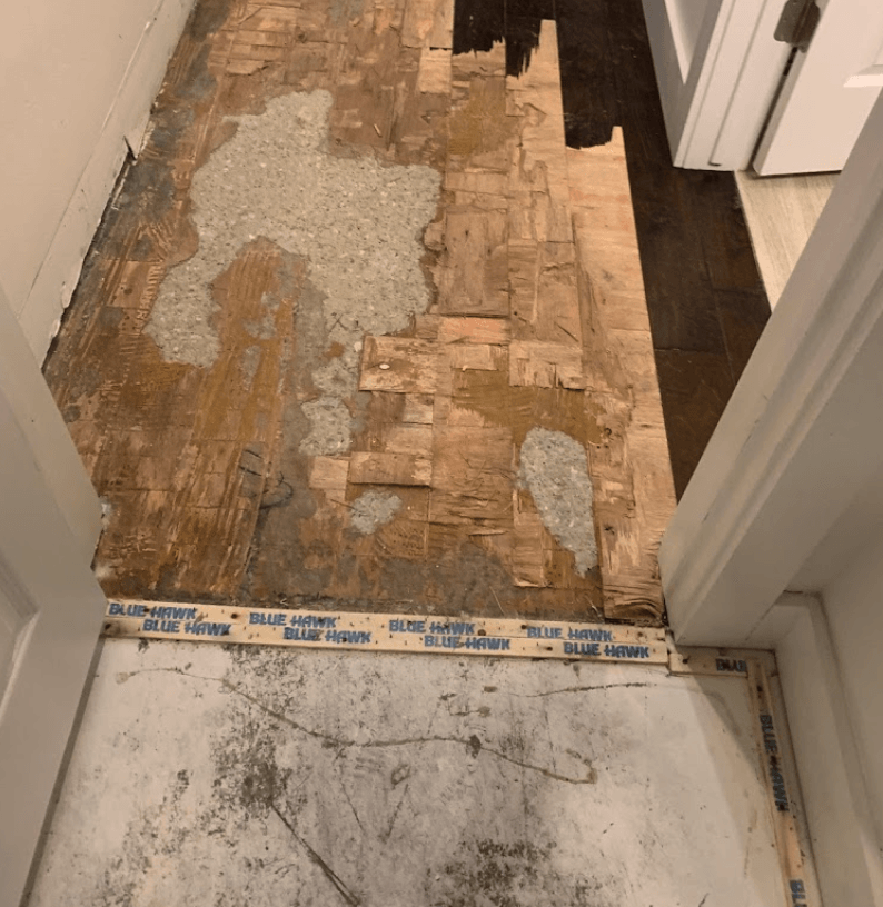 Damaged wood floor in doorway, from flood damage