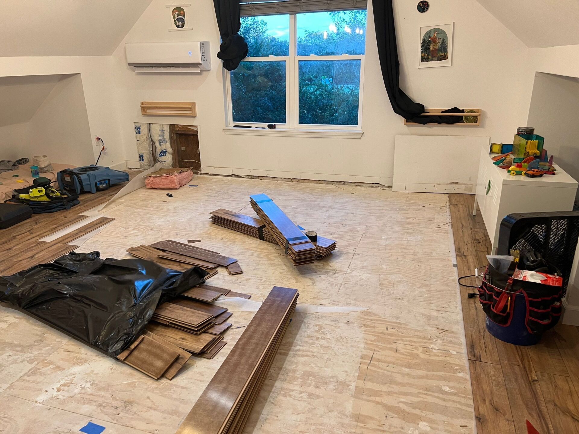 Room under renovation with flooring materials. Window in background.