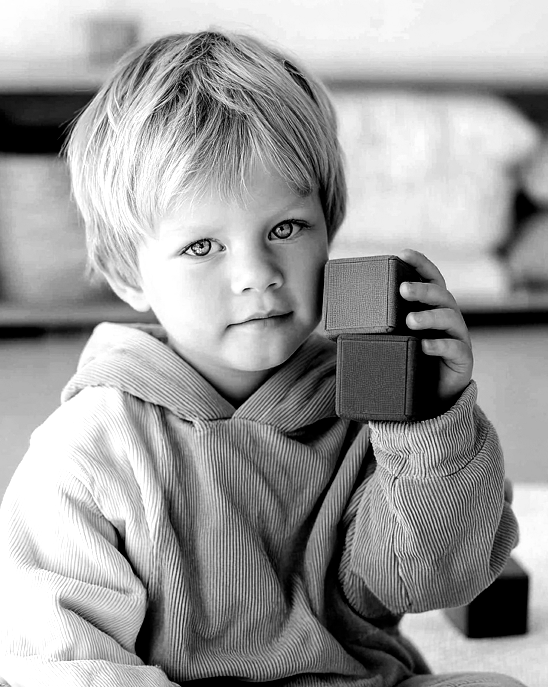 Boy writing in a notebook at a table, pencil in hand. Black and white photo.
