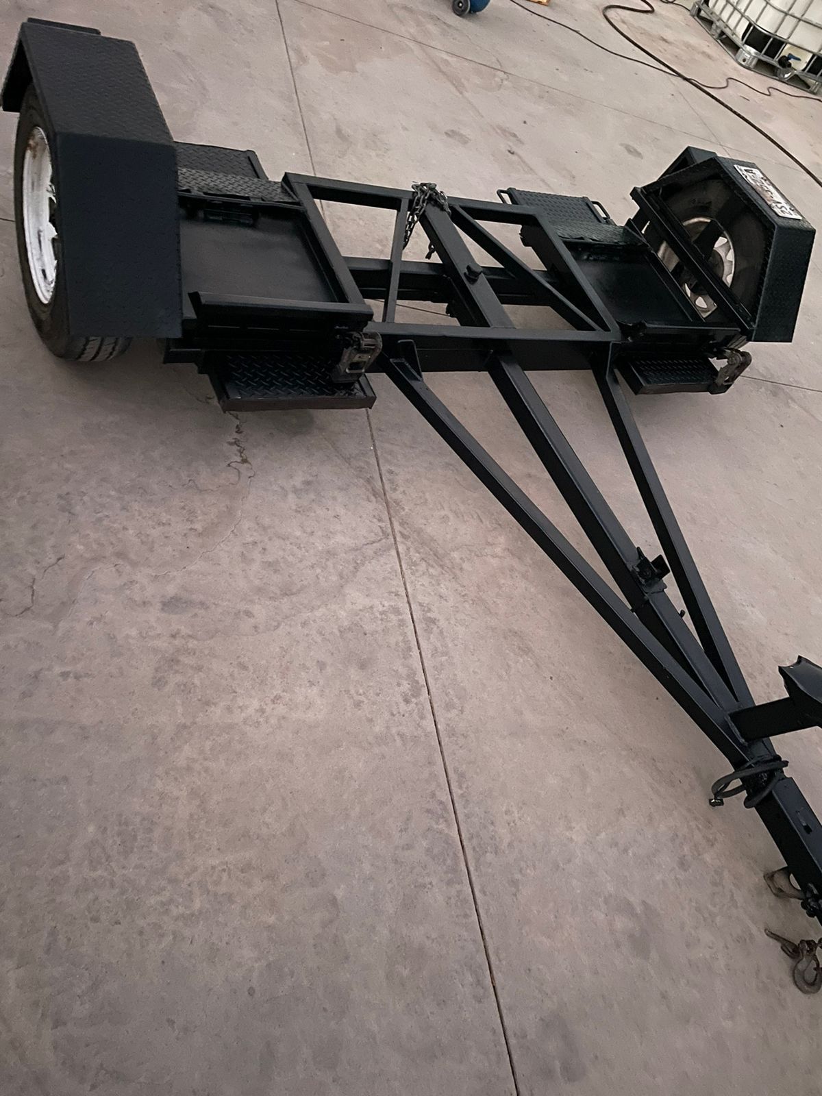 Un remolque negro se encuentra sobre una superficie de hormigón.