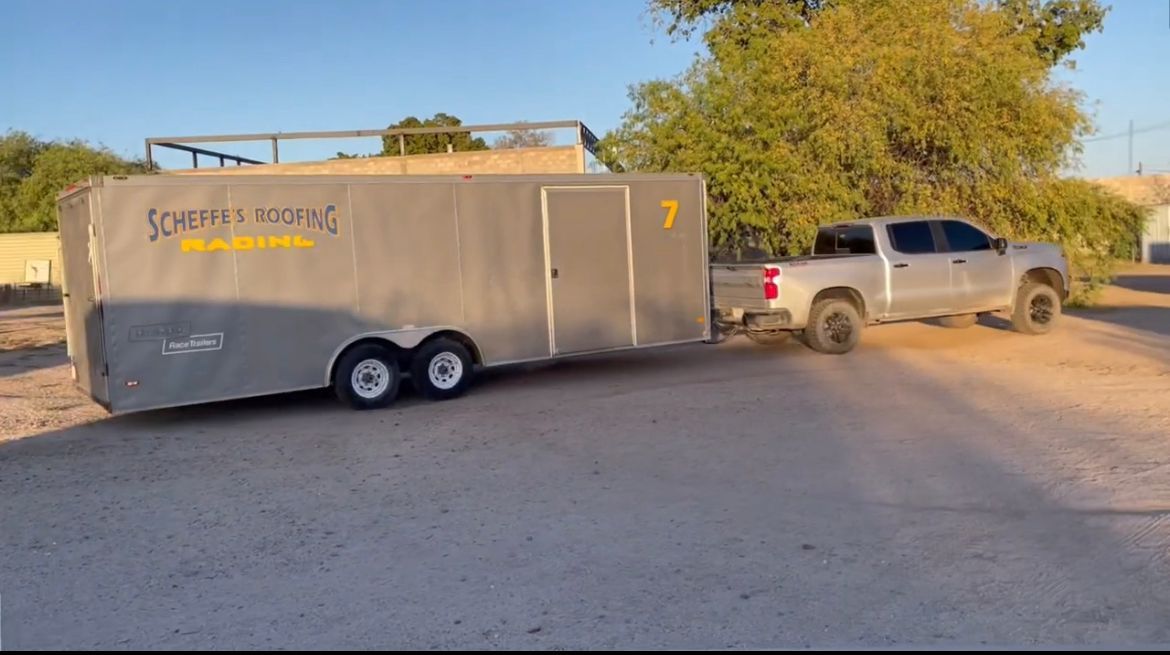 Un camión está arrastrando un remolque por un camino de tierra.