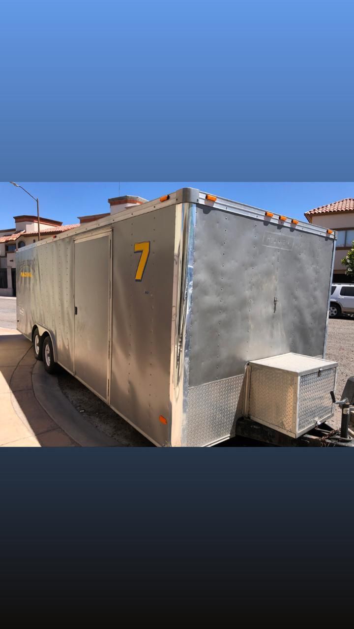 Un remolque plateado con el número 7 está estacionado en un estacionamiento.