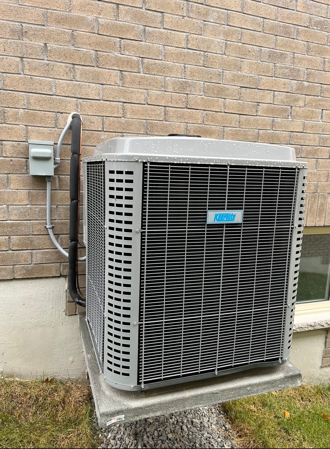 A large air conditioner is sitting on the side of a brick building.