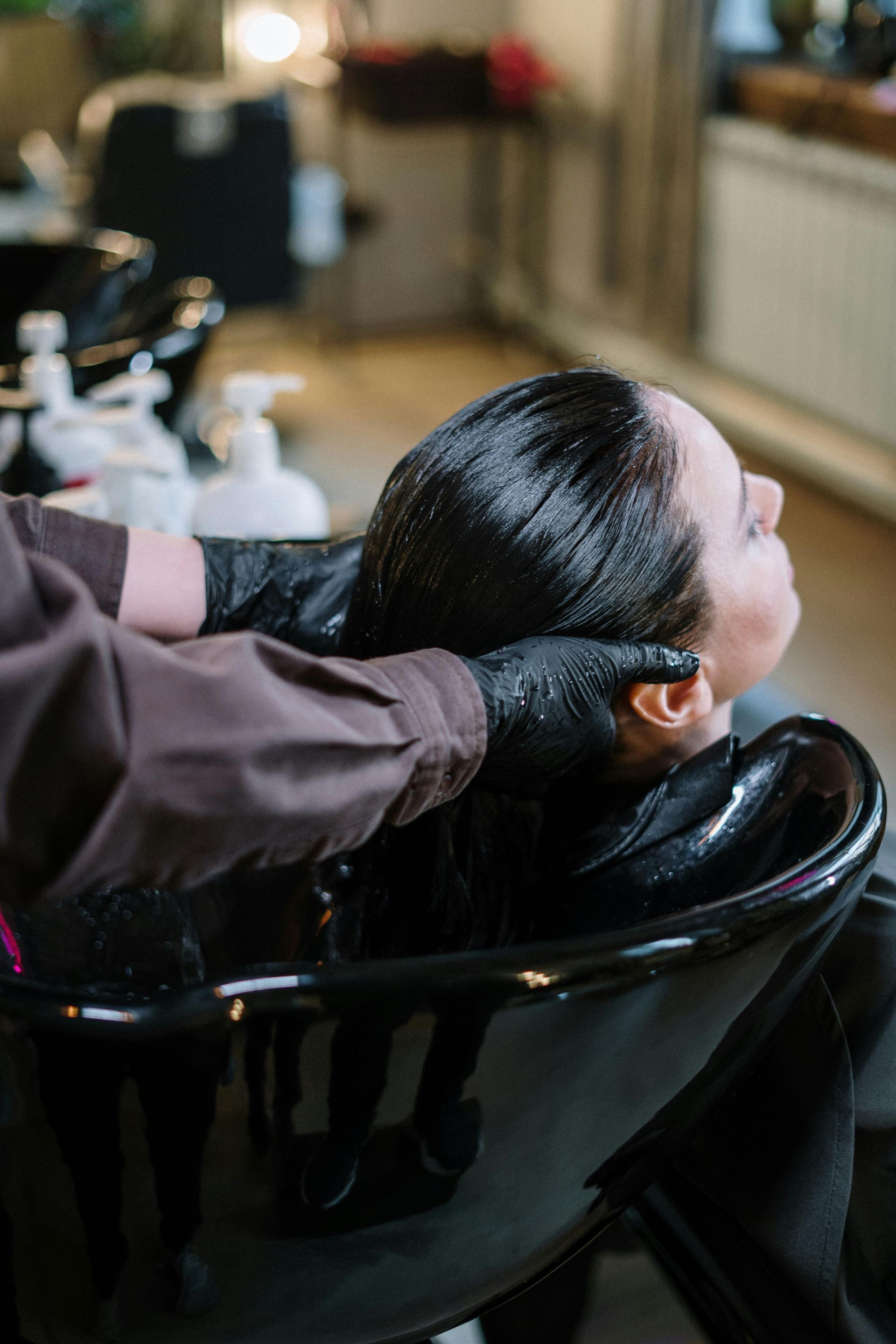 A woman is getting her hair washed in a sink at a salon.