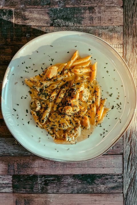 A white plate topped with pasta and sauce on a wooden table.