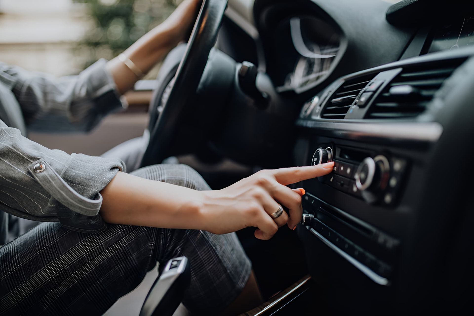 A Woman Is Driving A Car And Adjusting The Car Air Conditioner — Lismore Tecnicair In South Lismore, NSW