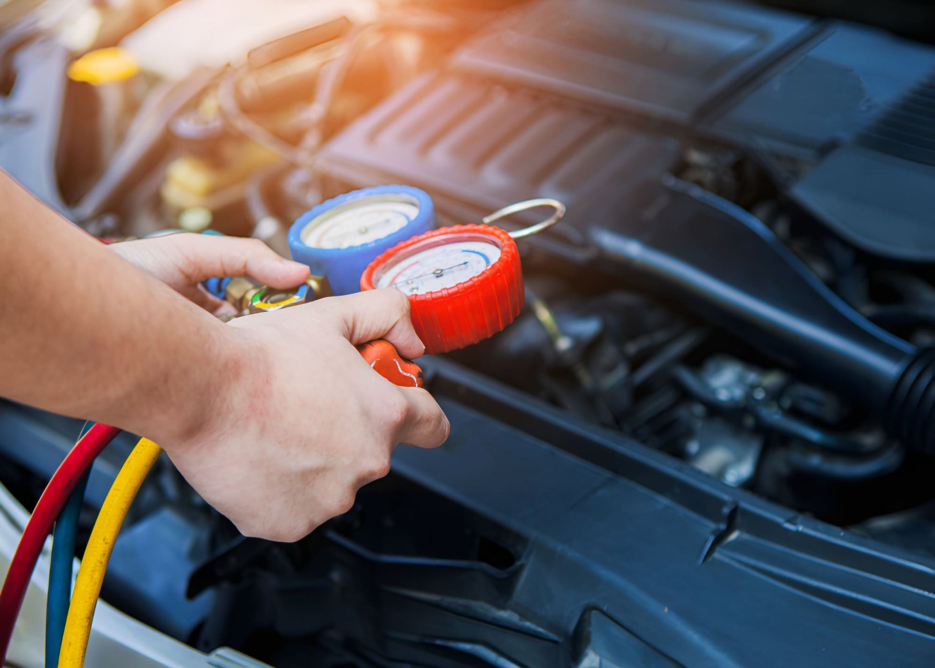 A Person Is Holding A Manifold Gauge In Front Of A Car Engine — Lismore Tecnicair In South Lismore, NSW