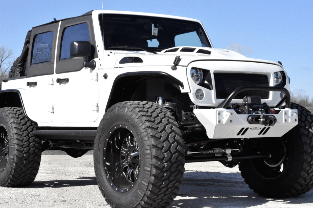 White Jeep Wrangler with oversized tires, black accents, and modified front end parked outdoors.