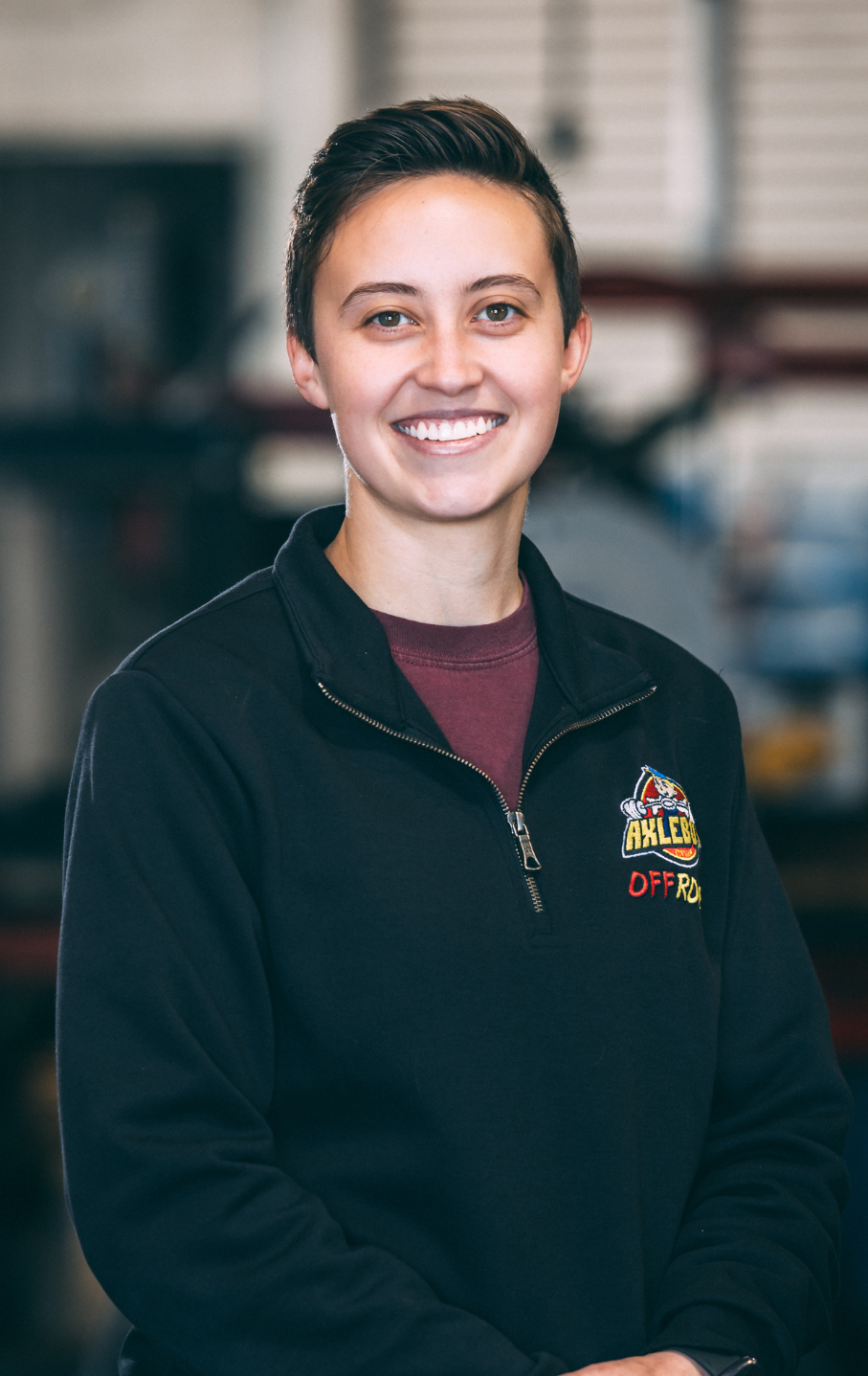 Young woman with short hair, smiling, wearing a black sweatshirt in a shop.