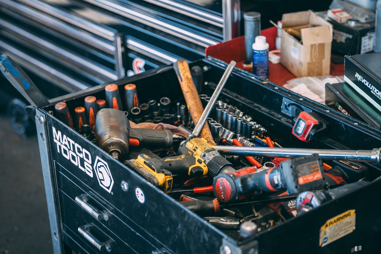 Black tool cart with open top, full of various tools like hammers and drills.