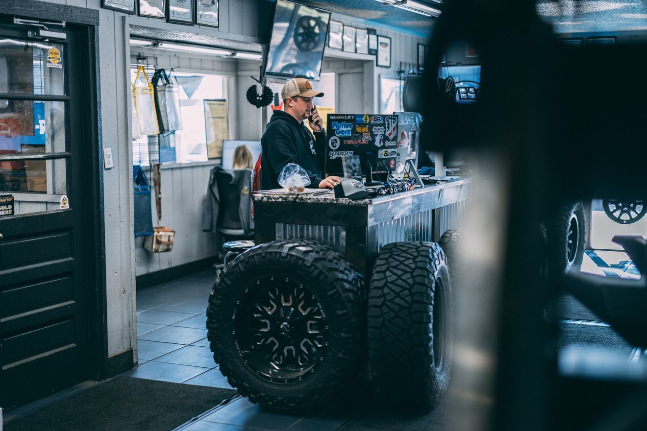 Man on phone at mechanic shop counter made of tires.