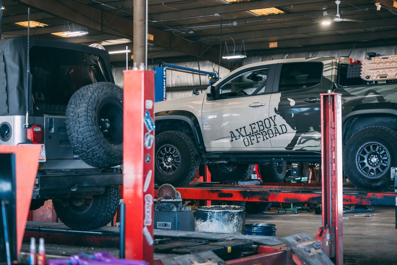 Jeep and truck on a lift in a garage. The truck has 