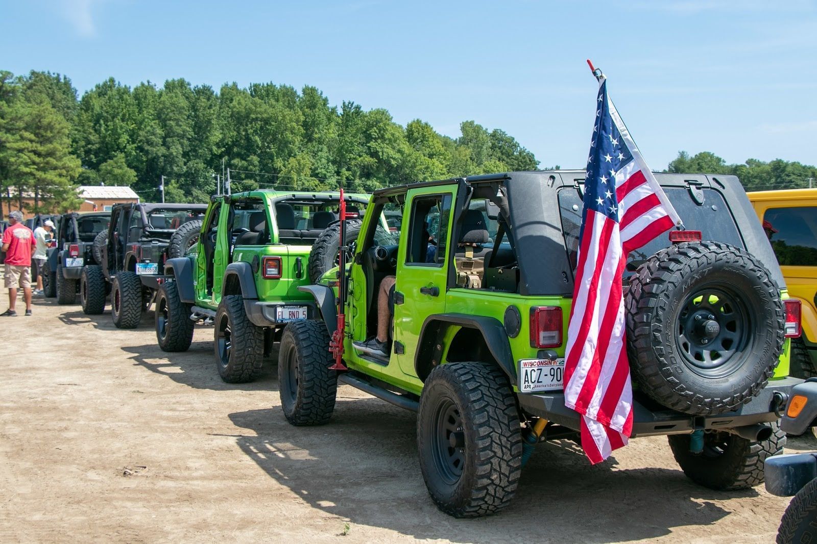 Line of green and black Jeeps with an American flag, parked outdoors.