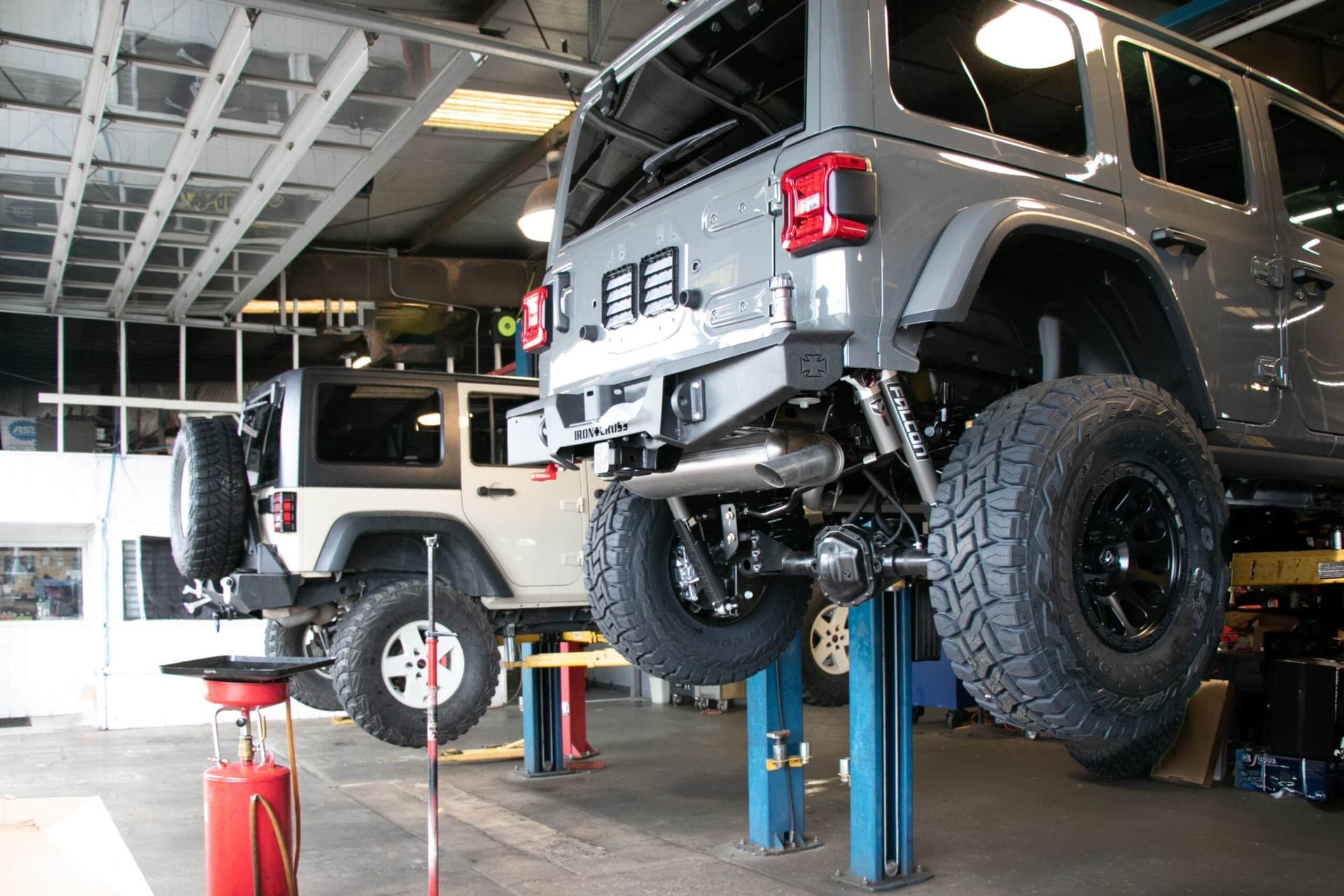 Professional technician installing suspension lift kit on pickup truck in clean automotive shop bay showing proper equipment