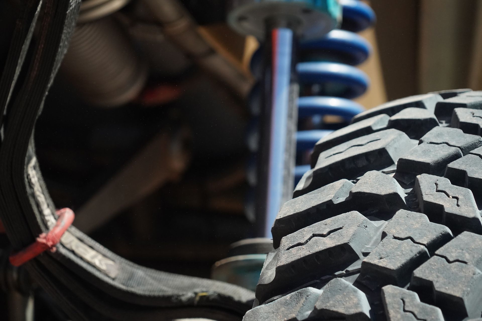Close-up of a lift-kit with black off-road tire with a blue coil spring suspension  upgrade  components.