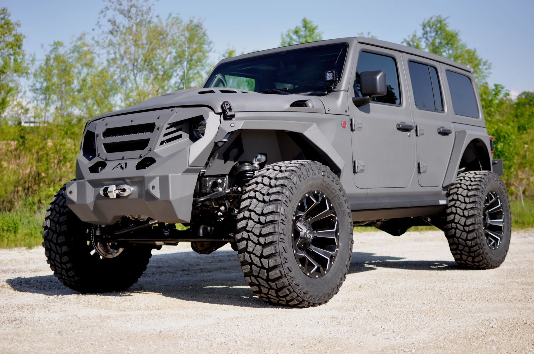 Gray modified Jeep Wrangler with large tires, outdoors.