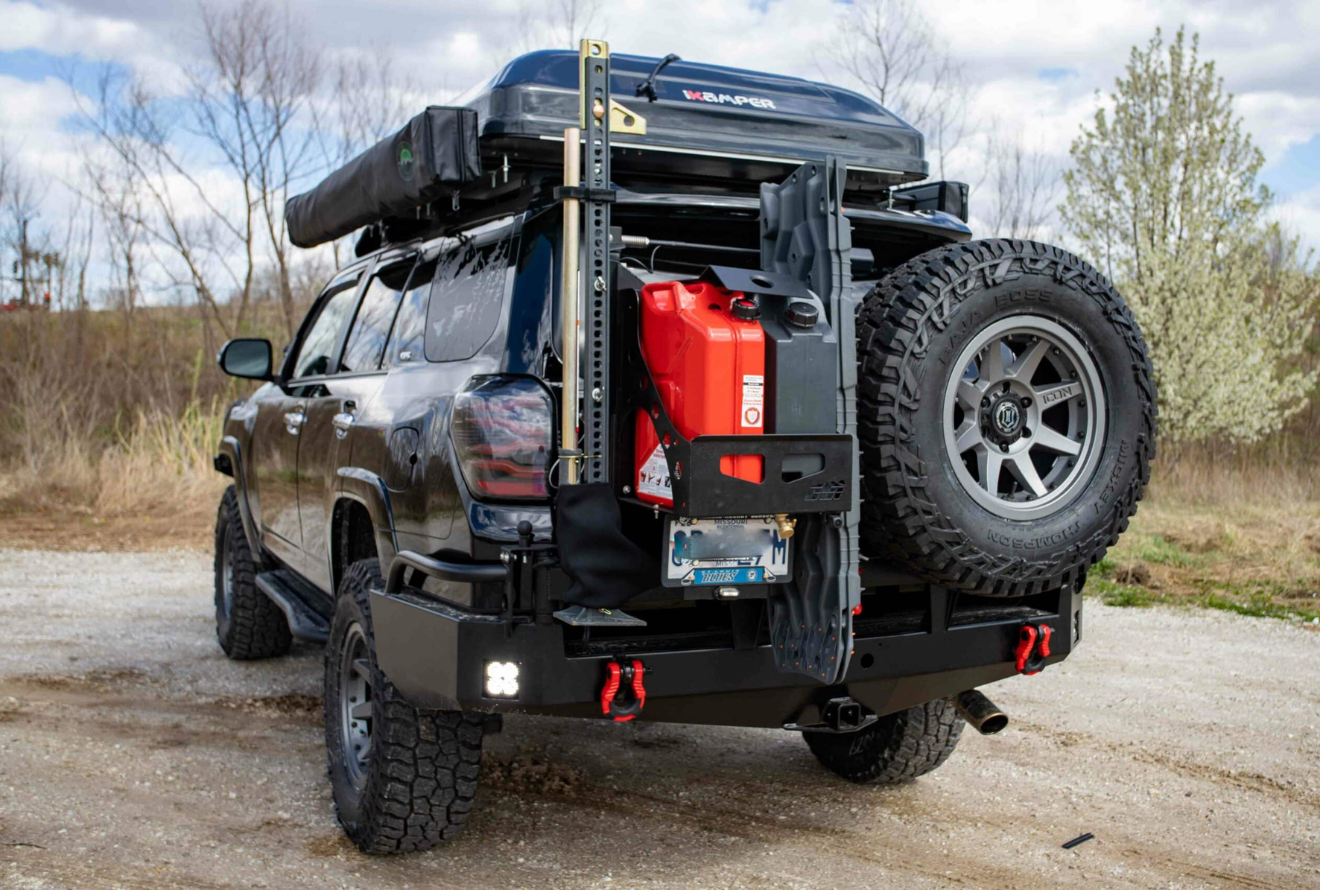Black SUV with roof rack, spare tire, and rear storage, parked outdoors.