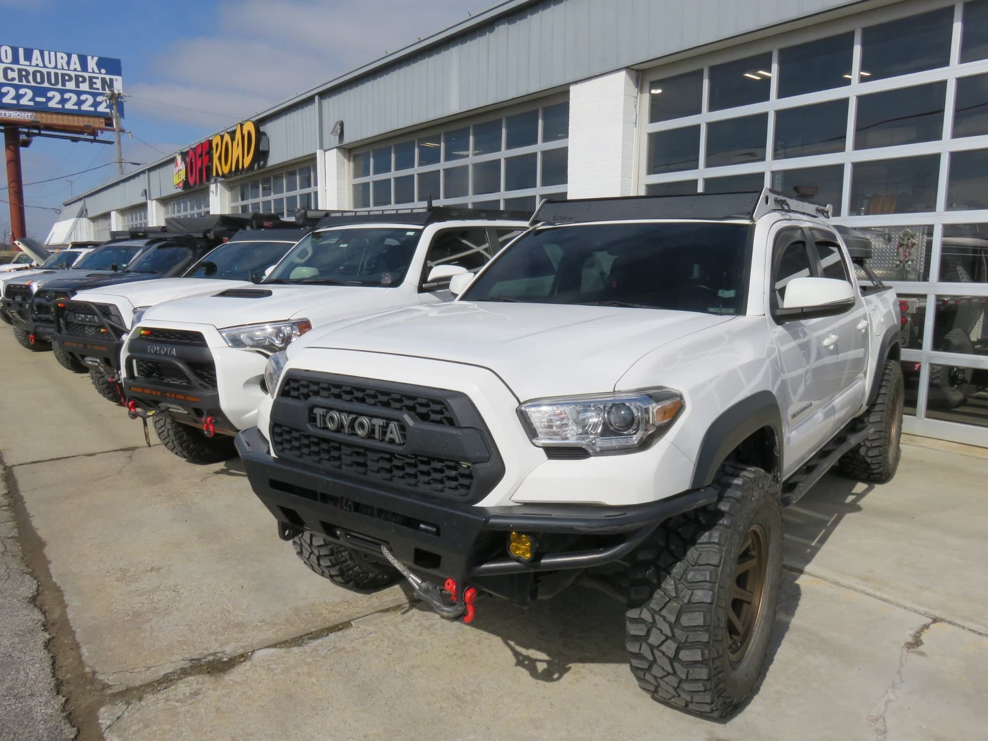 Line of white and black Toyota trucks parked outside a building.