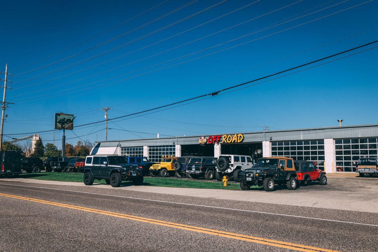 Jeeps parked in front of a dealership, blue sky.