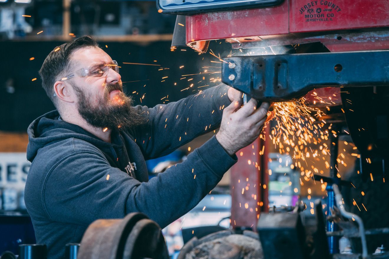 Man working at a cluttered desk with multiple computer screens. He is looking at the screens, in an indoor setting.