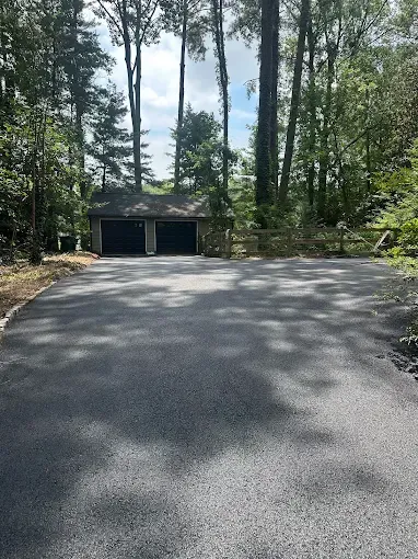 Driveway leading to a two-car garage in a wooded residential area
