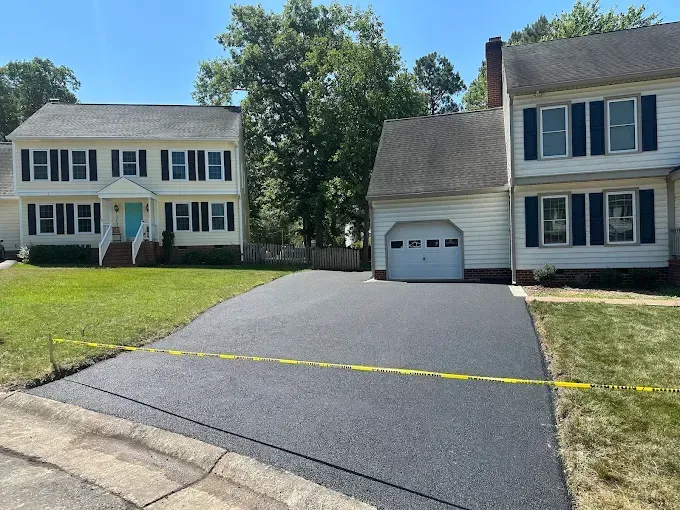 Suburban houses with a fresh black driveway and yellow caution tape across the front area