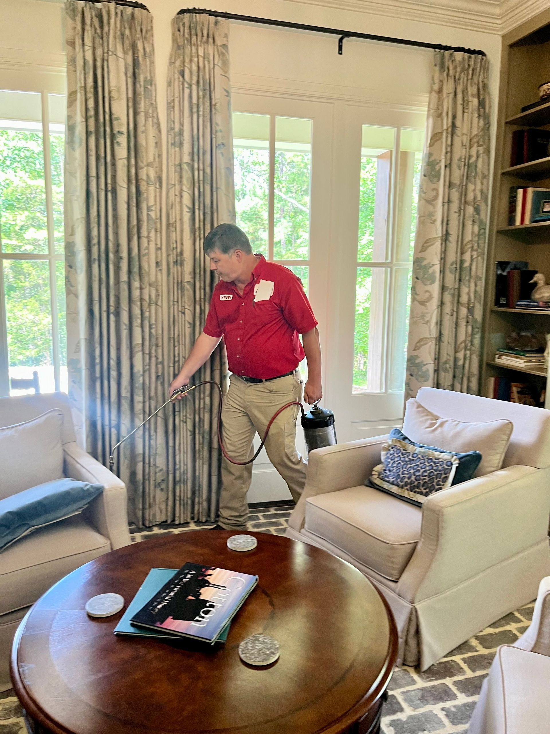 A man in a protective suit is spraying a bed with a sprayer.