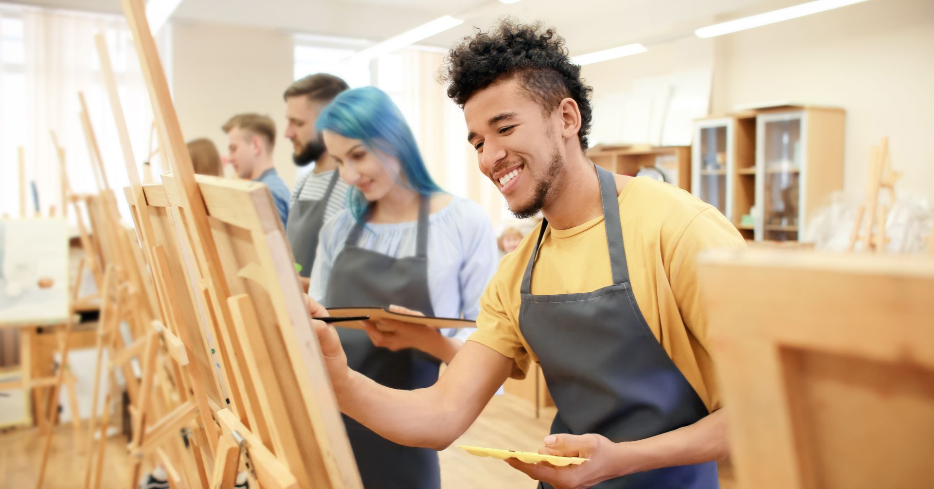 Young man painting with other young people in a workshop environment
