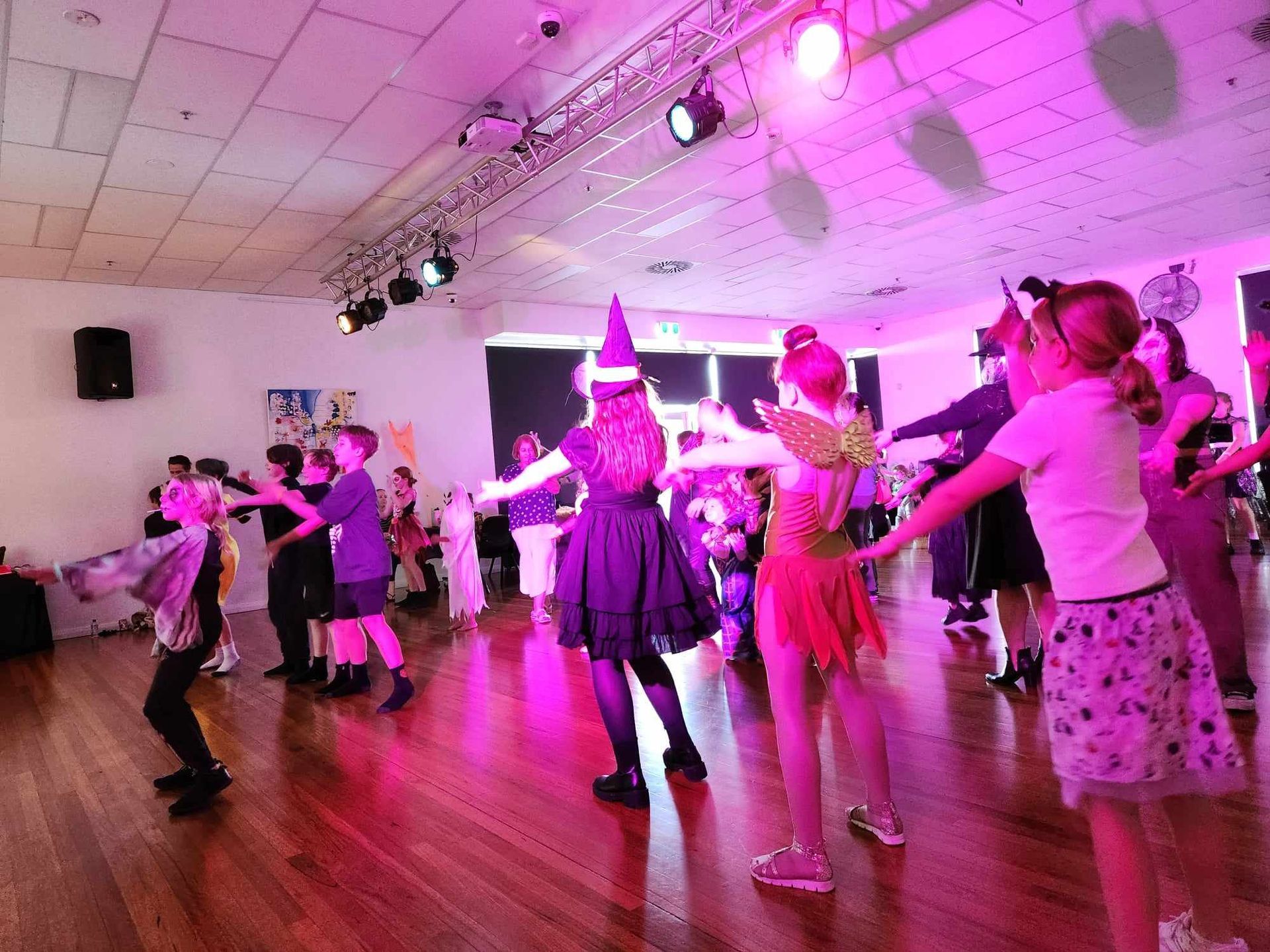 Group of people of all ages dressed up for halloween and dancing at a disco